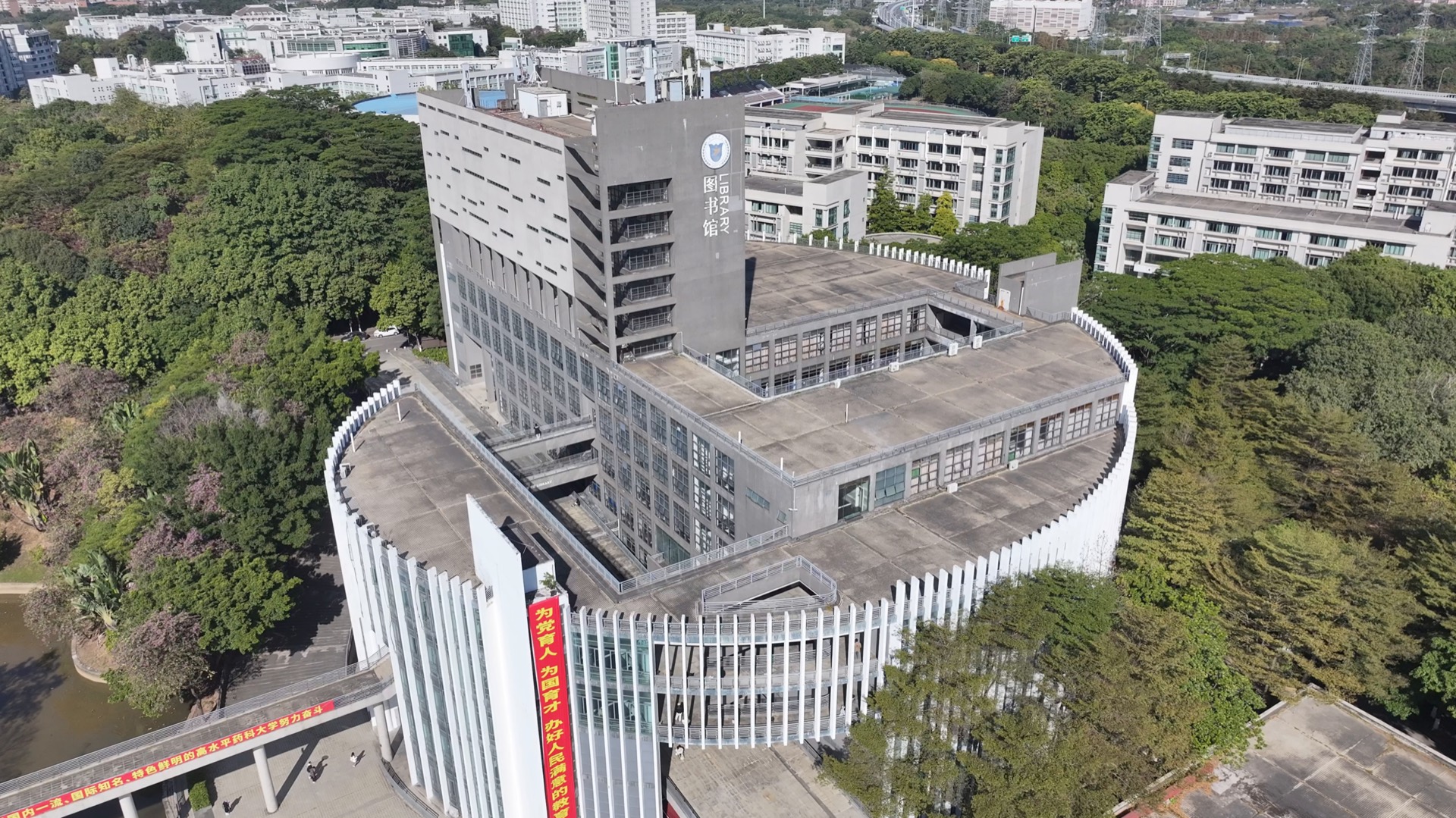 A UAV view of a campus library tower surrounded by trees and institutional buildings.