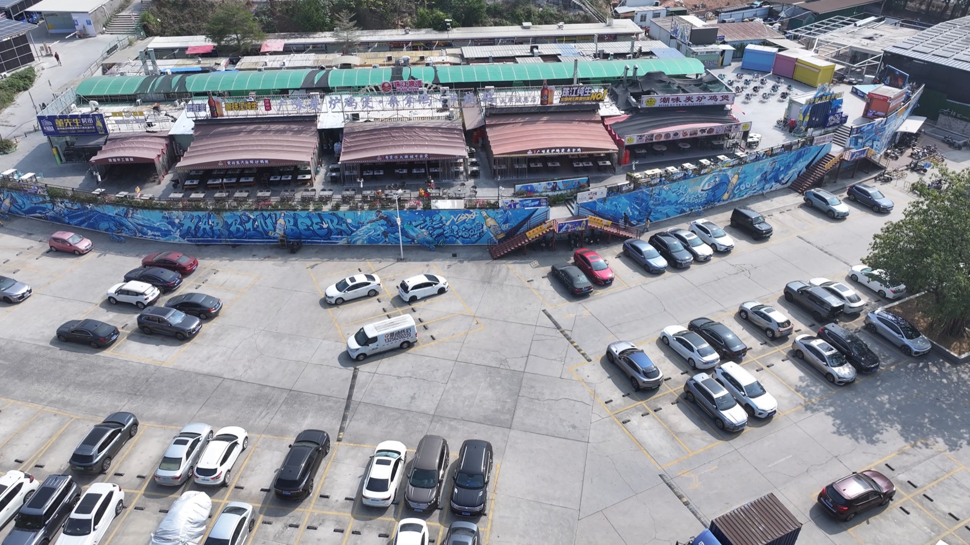 A UAV view of a market edge with parking lots, storefronts, and rich visual clutter.