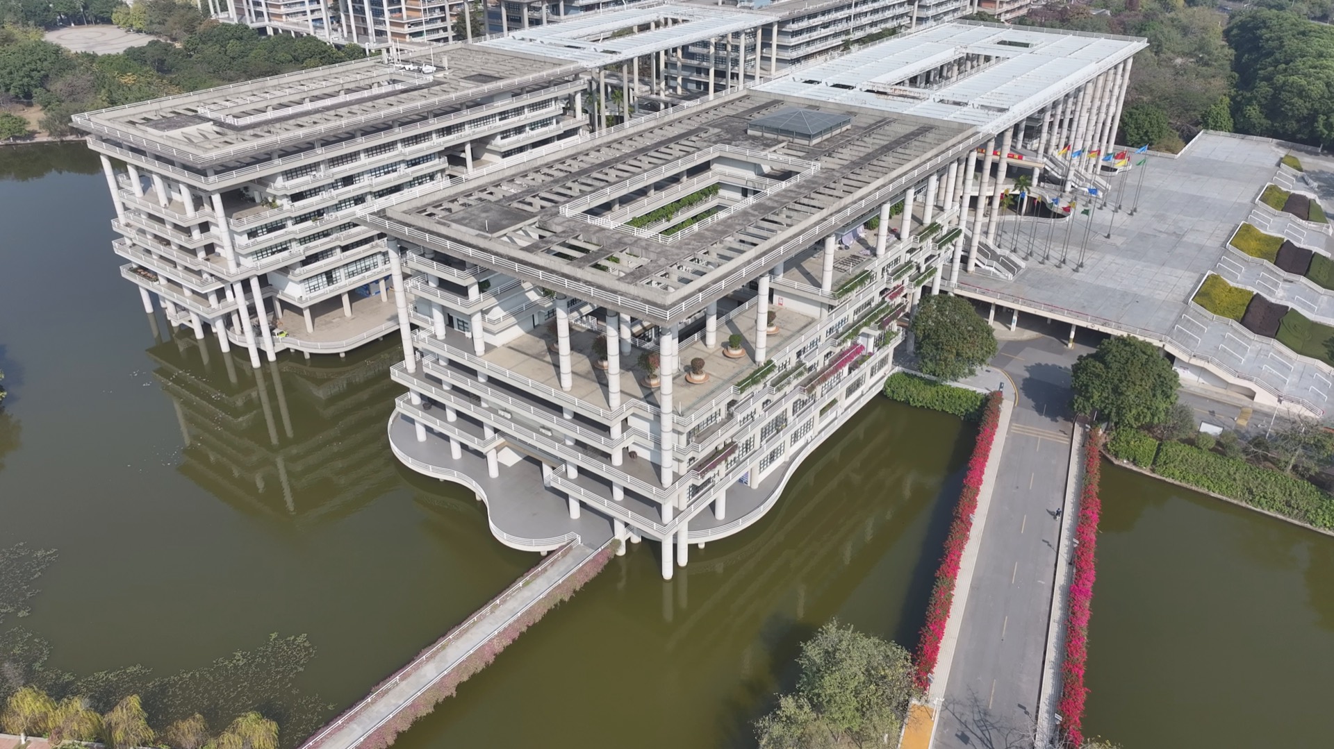 A UAV view of a large academic complex positioned above a waterside boundary.